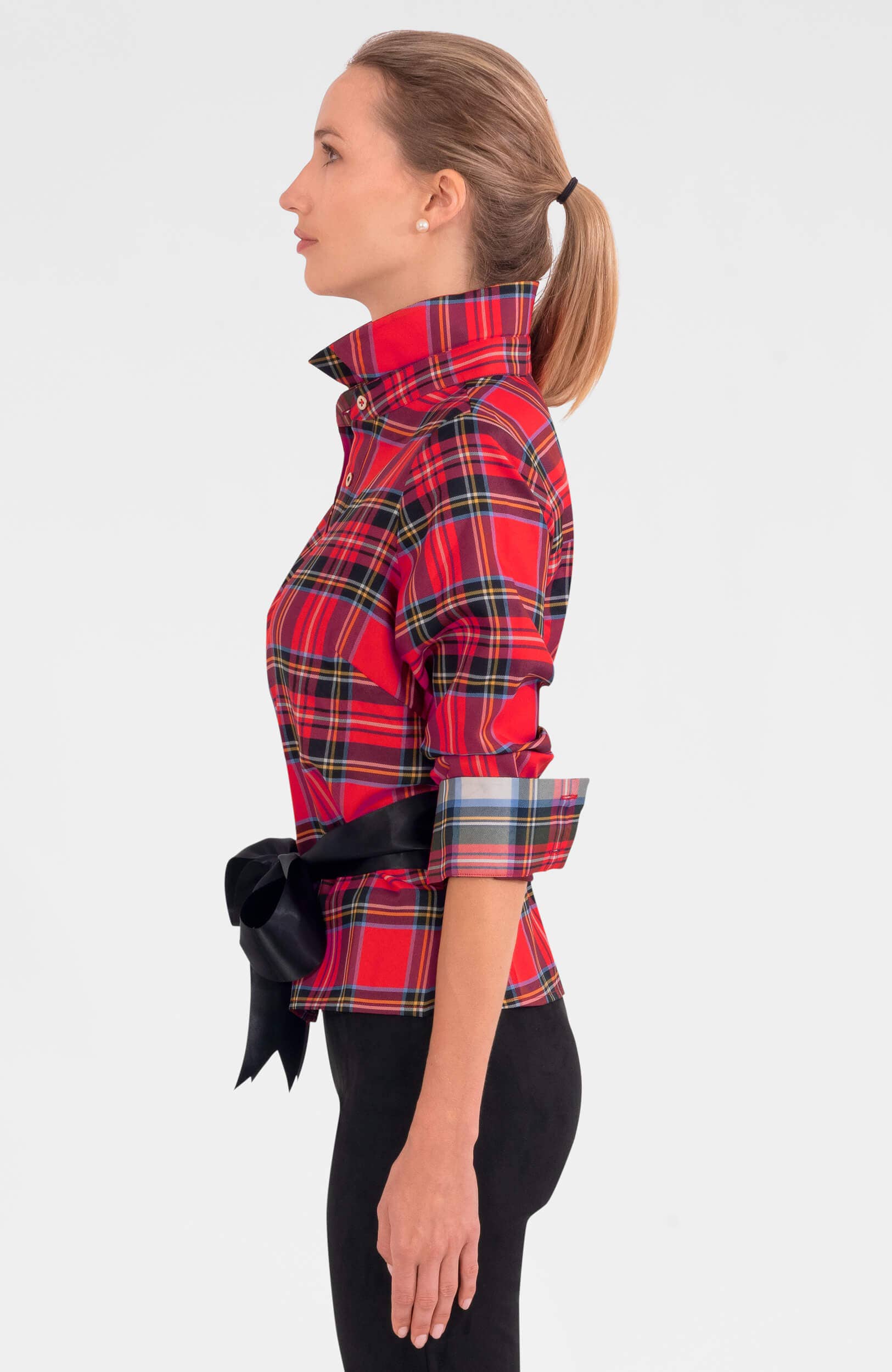 Woman wearing a red plaid shirt with a black bow on a white background